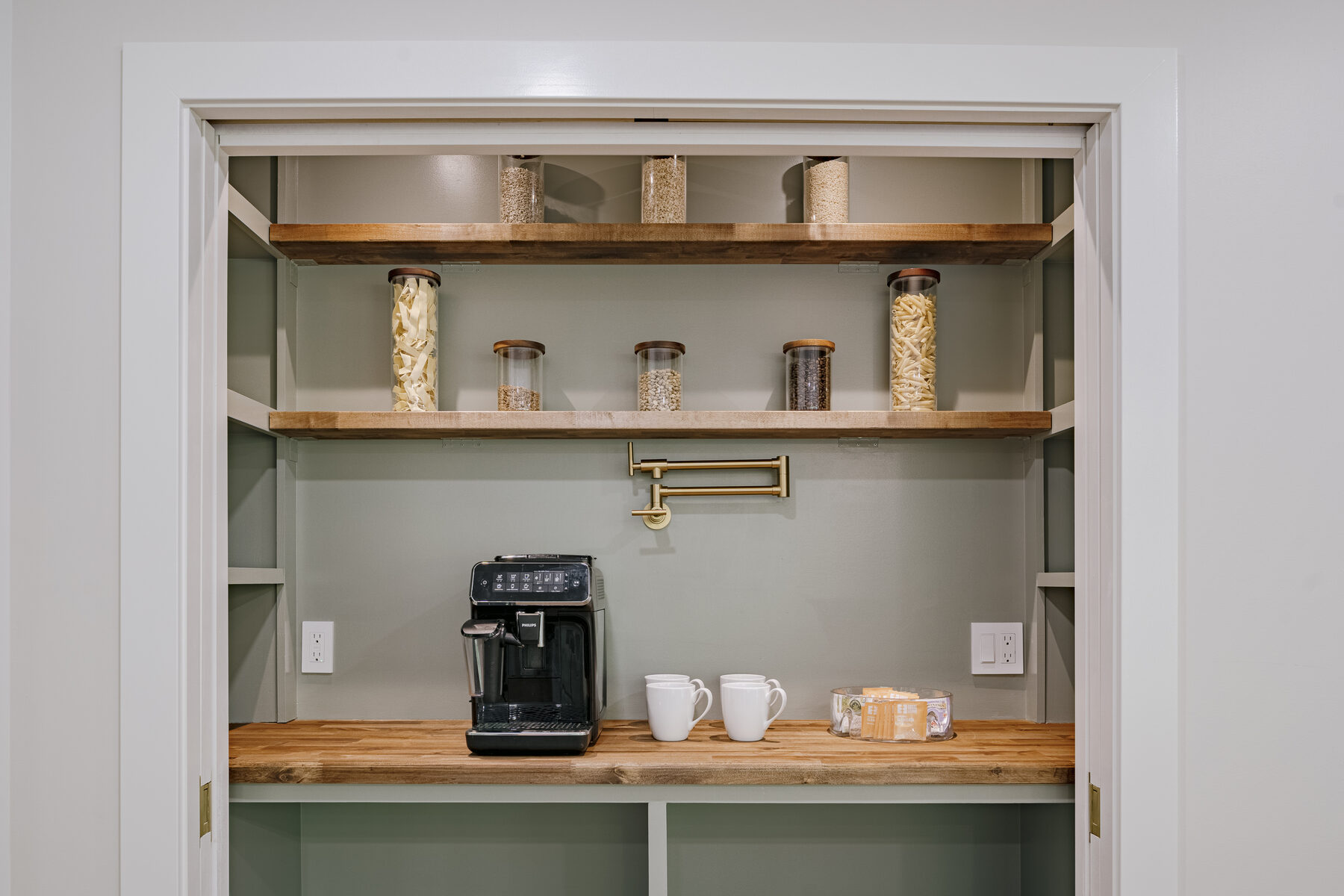 Sage-green butler's pantry with brass fixtures