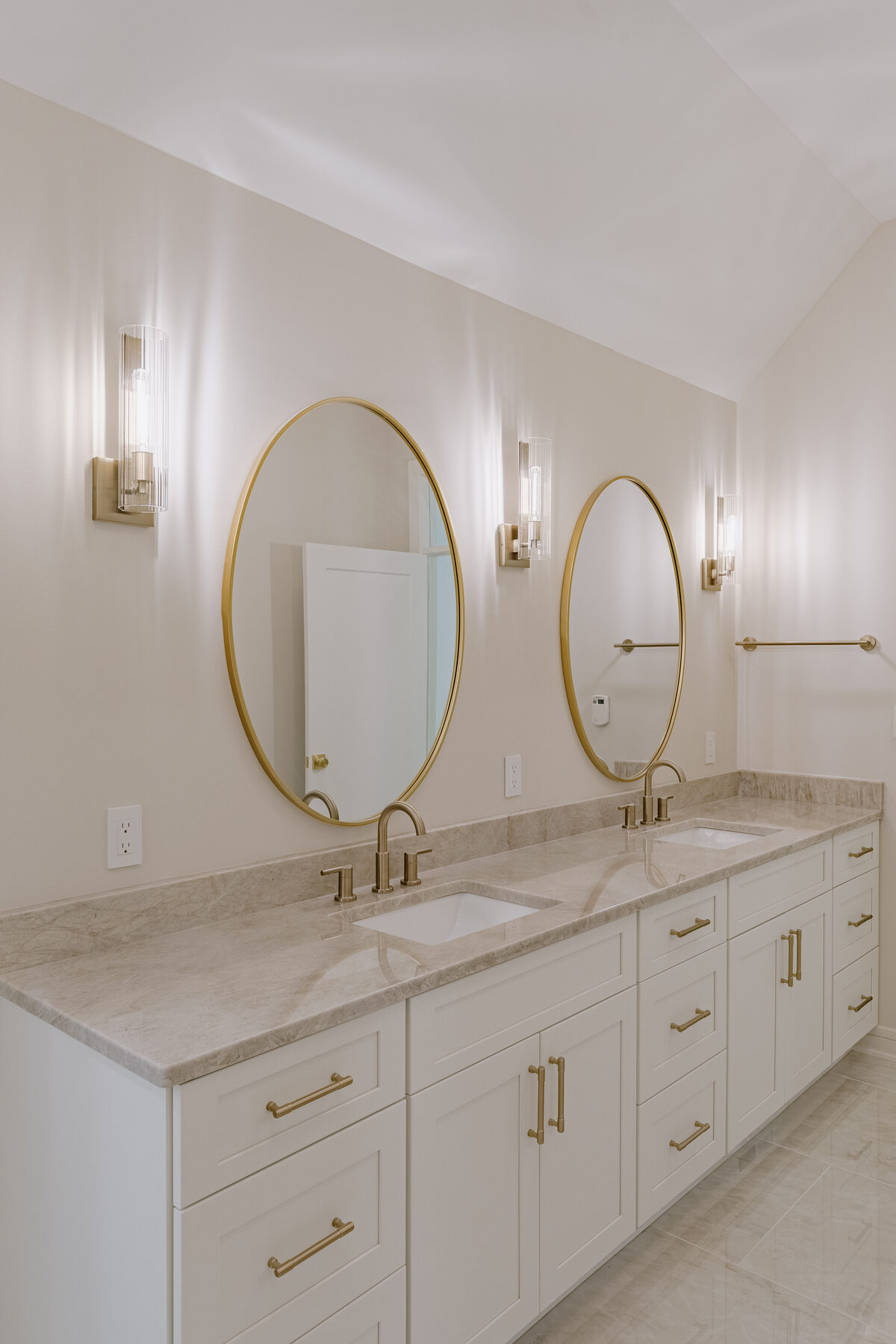 Primary bath — double vanity with brass mirrors and sconces